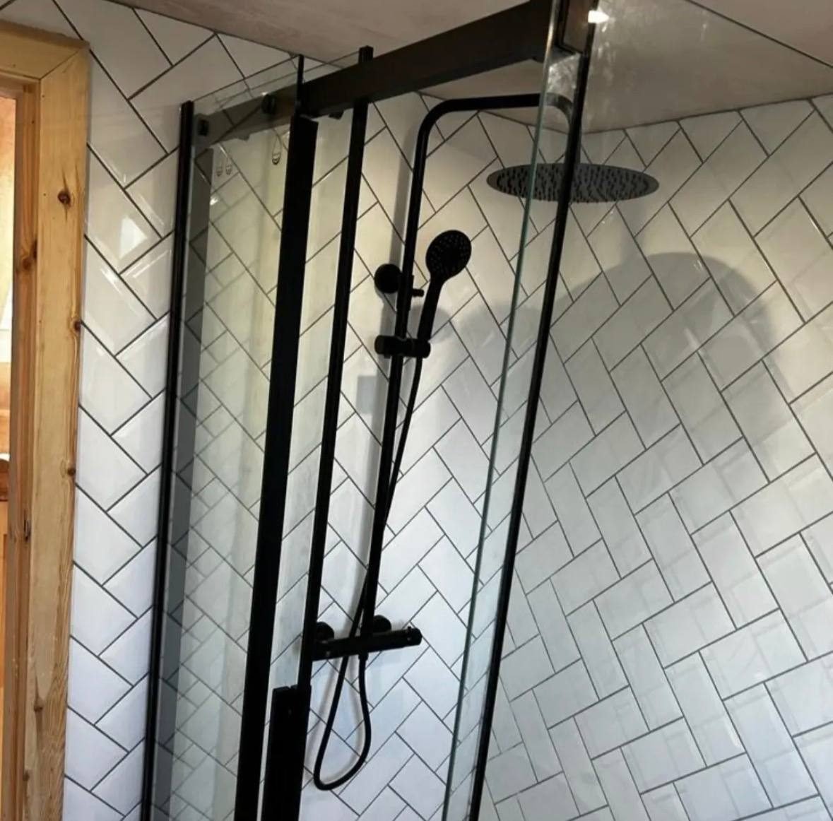 Herringbone-tiled shower enclosure with a matt black rainfall shower