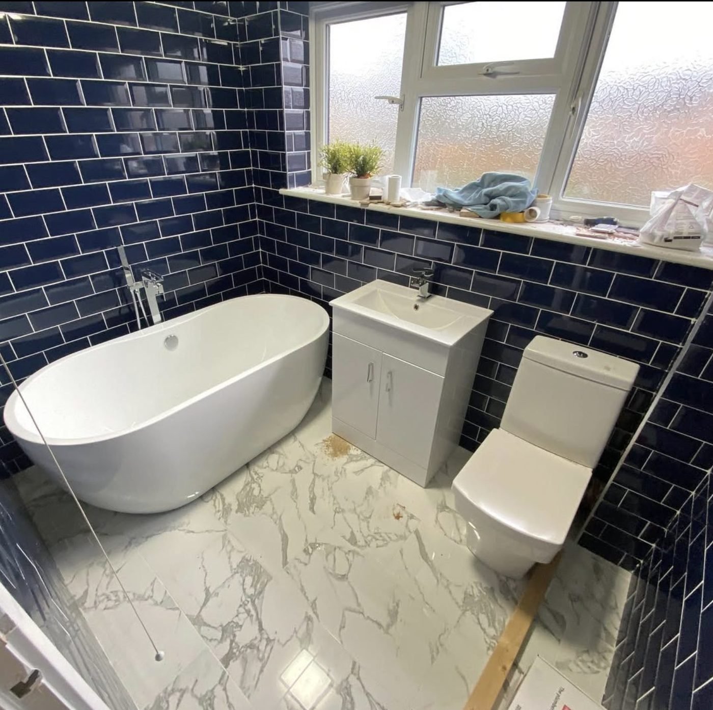 Navy metro tiling and a freestanding bath with marble-effect floor tiles